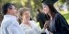 Female graduate in cap and gown talking to middle-aged couple.