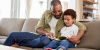 Young adult African-American man reading to African-American toddler.
