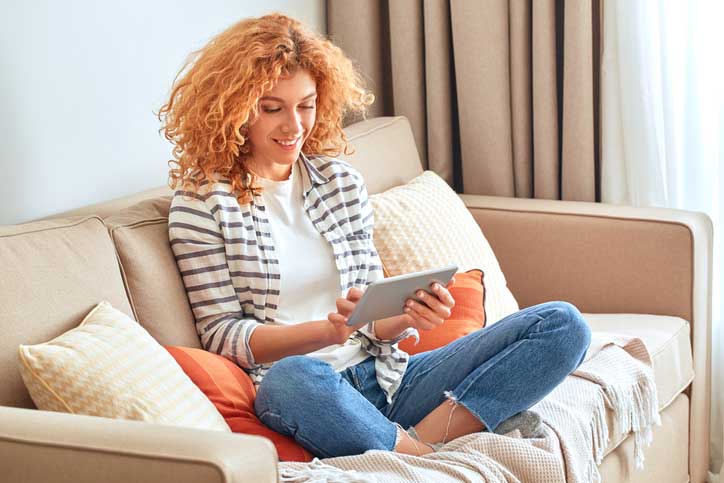 woman reading more information about how personal loans can benefit her comfortably on her couch